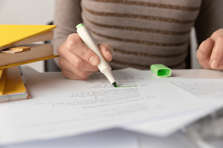 Close-up view of a desk with various stationery items, books, and papers related to A-Level exams.